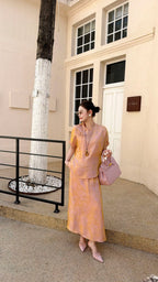 Model wearing a soft pink short sleeve Cheongsam top and matching midi skirt, holding a pink bag, perfect for elegant summer styling.