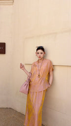 Full body shot of a viscose blend Cheongsam set in champagne rose, featuring a buttoned top and flowy side-slit skirt, paired with nude heels.