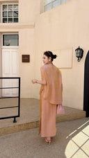 Back view of a champagne pink Cheongsam co-ord set with short sleeve top and side slit skirt, crafted from 80% viscose and 20% nylon, paired with pink heels.