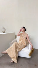 Sitting woman in a sleeveless Cheongsam vest set in champagne gold, featuring a mandarin collar and palazzo trousers.