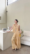 Sitting woman in a sleeveless Cheongsam vest set in champagne gold, featuring a mandarin collar and palazzo trousers.