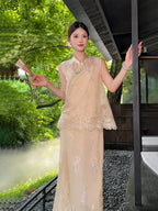 Model wearing a champagne gold sleeveless Cheongsam vest with bead embroidery and lace hem, paired with a matching skirt, holding a fan in a garden setting.