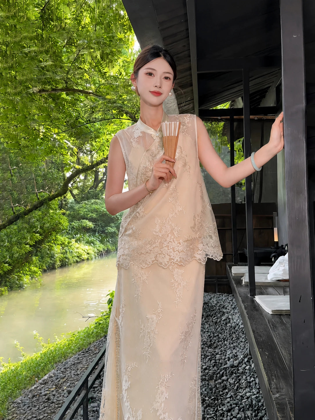 Front view of a champagne gold sleeveless vest with bead embroidery and a matching A-line skirt with lace panels, styled with a fan.