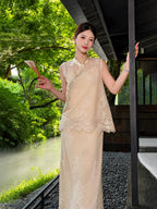 Full body shot of a champagne gold sleeveless vest and midi skirt set with bead embroidery and lace details, holding a folded fan.