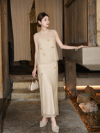 Side view of a champagne sleeveless top and skirt set with scattered floral details and side slit, styled with pearl shoes, crafted from Lyocell and Tencel.