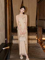 Front view of a champagne Cheongsam set featuring a sheer neckline and 3D floral appliqués, holding a pleated handbag.