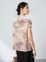 Back view of a champagne jacquard top with a stand collar and cap sleeves, featuring an abstract watercolor print, paired with a black skirt.
