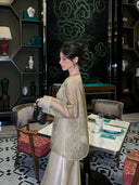 Woman wearing a lightweight Champagne Sage silk cardigan with a relaxed silhouette in an elegant interior.