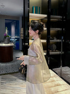 Side view of a woman wearing a Champagne Sage pure silk sheer cardigan layered over an ivory satin dress.