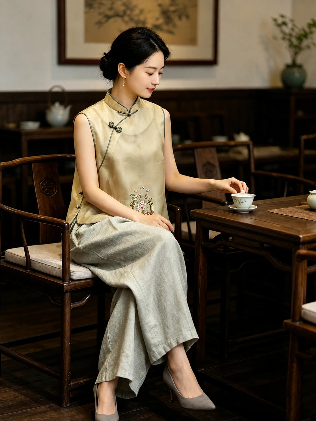 Chinese-inspired champagne yellow silk vest with floral embroidery worn in a traditional tea setting