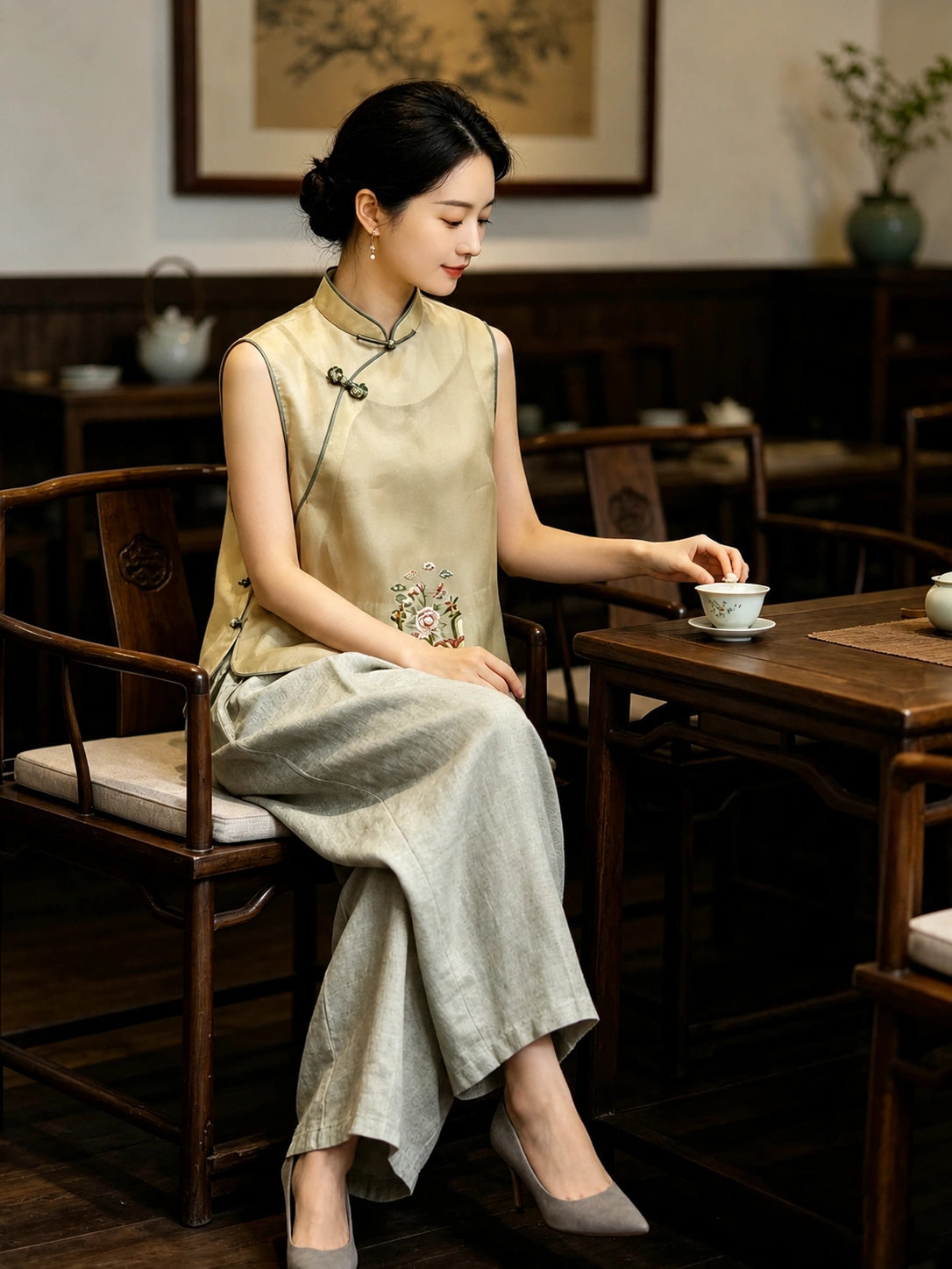 Chinese-inspired champagne yellow silk vest with floral embroidery worn in a traditional tea setting