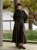 Front view of the charcoal olive blouse with a stand collar, off-centre buttons and a shaped waist above the skirt.