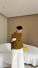 Woman wearing olive green wool-blend Cheongsam top with metallic brocade, holding a white tea cup, showcasing vintage texture and relaxed fit.