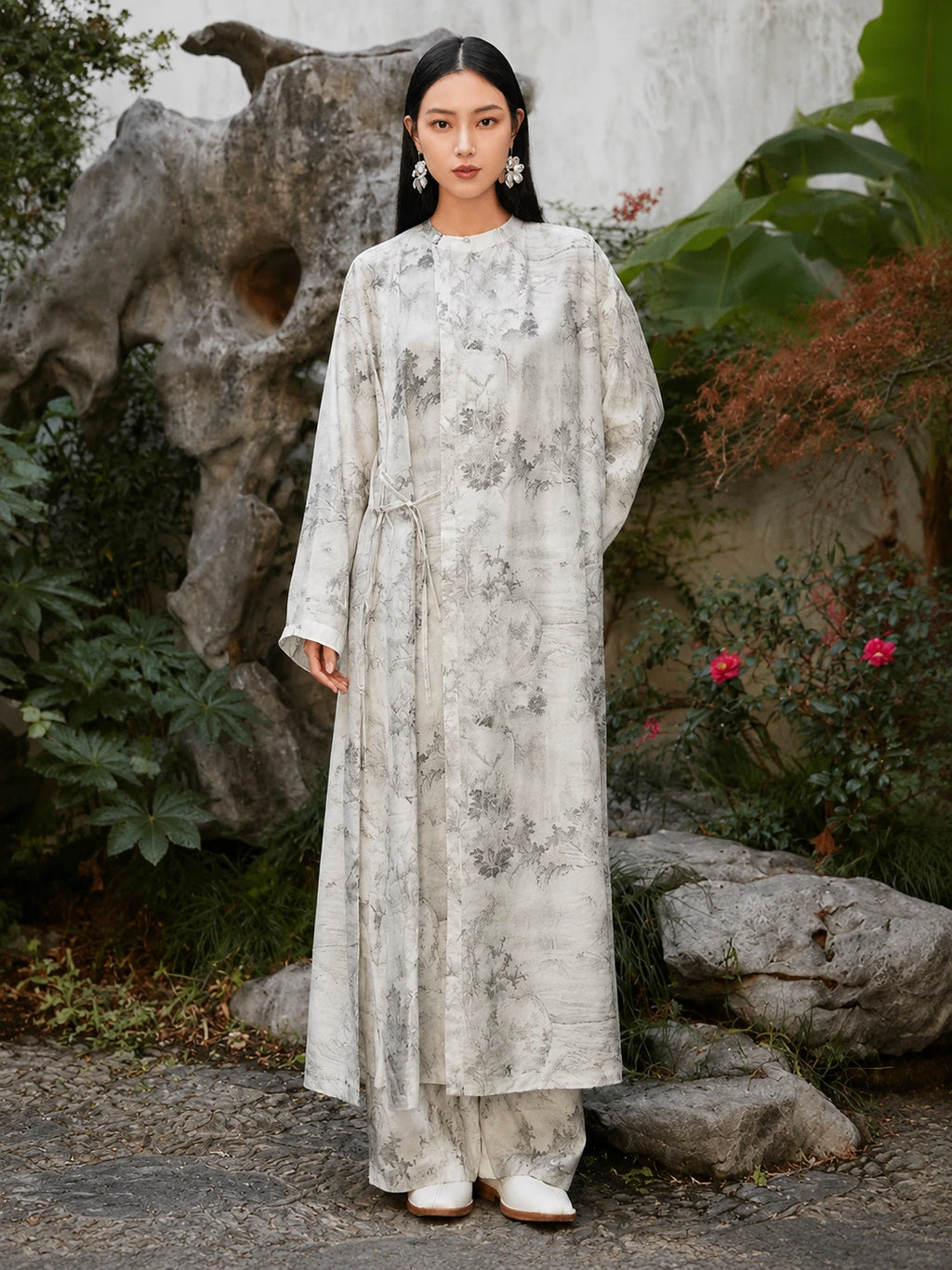 Woman wearing an ivory Chinese ink landscape print maxi dress with long sleeves, round neckline and adjustable side tie waist, front view.