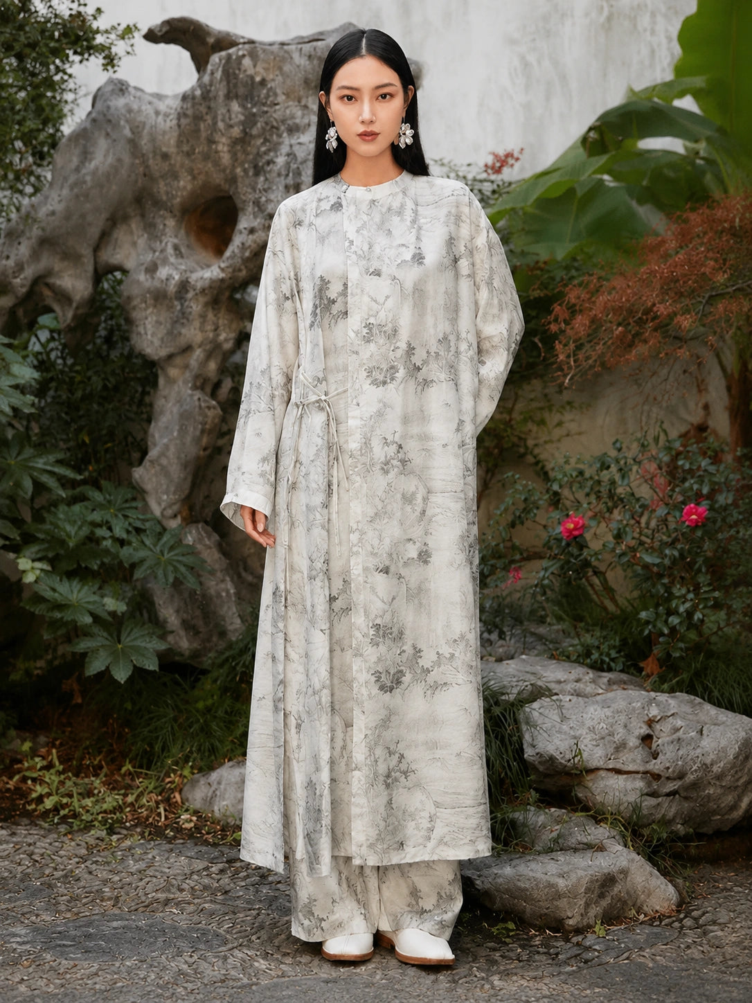 Woman wearing an ivory Chinese ink landscape print maxi dress with long sleeves, round neckline and adjustable side tie waist, front view.