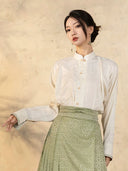 Close-up of a women's Mandarin collar blouse featuring subtle jacquard texture and frog-button detail.