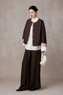 Angled full-length styling view of the cocoa-brown jacket with contrast pink cuffs