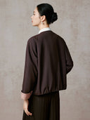 Back view of the model wearing the cocoa-brown jacket with a gathered hem