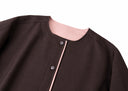 Close-up of the round neckline, snap buttons and blush-pink inner facing