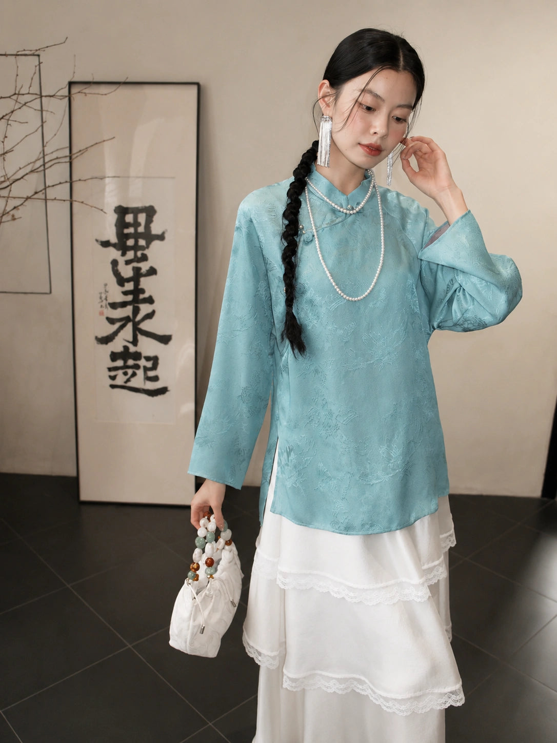 Model wearing a cooling blue 100% mulberry silk Hualuo Mandarin collar shirt with a white layered skirt