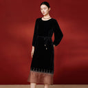 Angled view of the black velvet dress with its adjustable tie waist and embellished skirt border