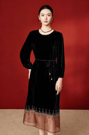 Front view of a model wearing the black velvet midi dress against a red background