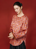 Angled view of the coral pink blouse, showing its geometric and floral print, curved hem and side slit.