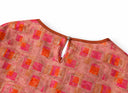 Close-up of the coral pink blouse’s back keyhole opening and button-and-loop fastening.