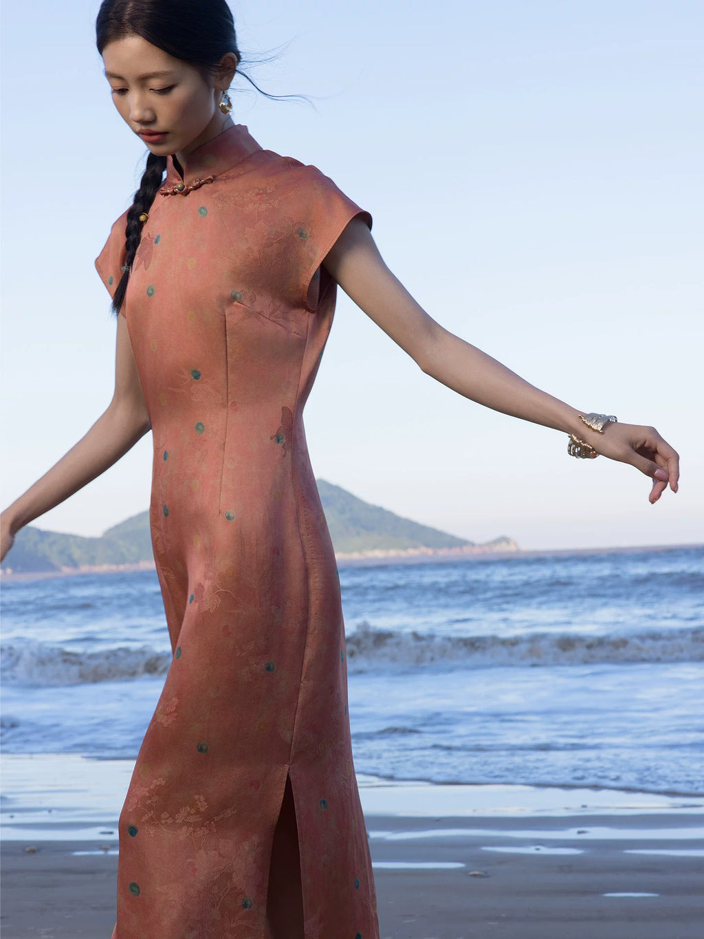 Side view of a coral silk blend Chinese style maxi dress featuring a mandarin collar and side slit.