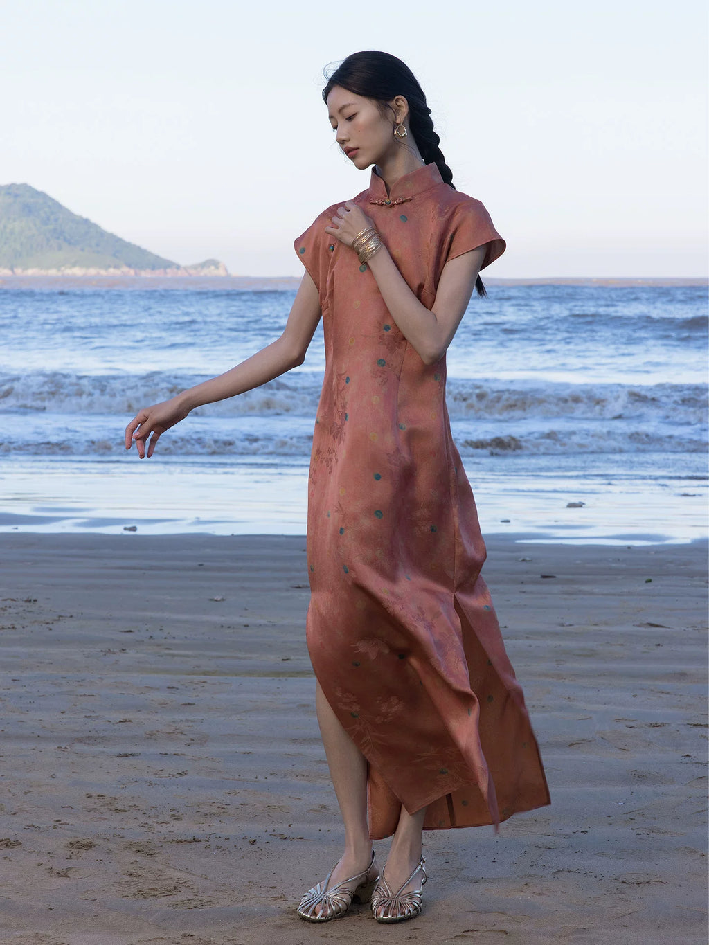 Woman walking along the beach wearing a Coral Sunset silk blend Chinese style maxi dress.