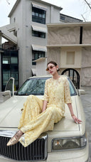 Model sitting on a vintage car hood wearing a cream Cheongsam set with short sleeves and palazzo pants, looking chic in sunglasses.