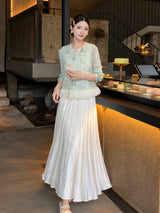 Model wearing a mint green sheer top with a cream white shiny pleated maxi skirt, showcasing the soft drape of the 100% polyester fabric.