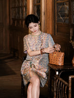 Model seated in a cream silk dress with purple and blue heritage-inspired geometric pattern