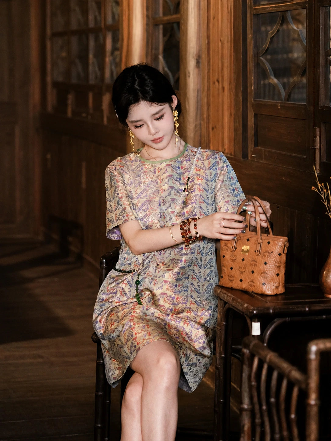 Model seated in a cream silk dress with purple and blue heritage-inspired geometric pattern