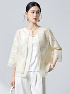 Model wearing a cream white silk organza cardigan with intricate embroidery, styled with white trousers, highlighting the versatile open-front design.