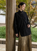 Model wearing the Jinyu Black shirt beside a wooden pillar.