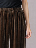 Close-up of the gathered waistband and soft velvet texture on dark brown wide-leg pants