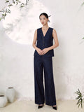 Full body shot of a deep blue silk two-piece set featuring a V-neck sleeveless vest with button-down front and contrast stitching, paired with matching wide-leg trousers, crafted from 100% mulberry silk, styled with black heels.