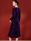Back view of the purple velvet dress on a model, showing the waist tie and small neckline opening.