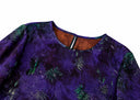 Close-up of the purple blouse’s bound round neckline and green foliage print.