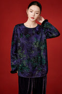 Model showing the purple blouse’s long flared sleeve, black textured cuff and all-over foliage print.