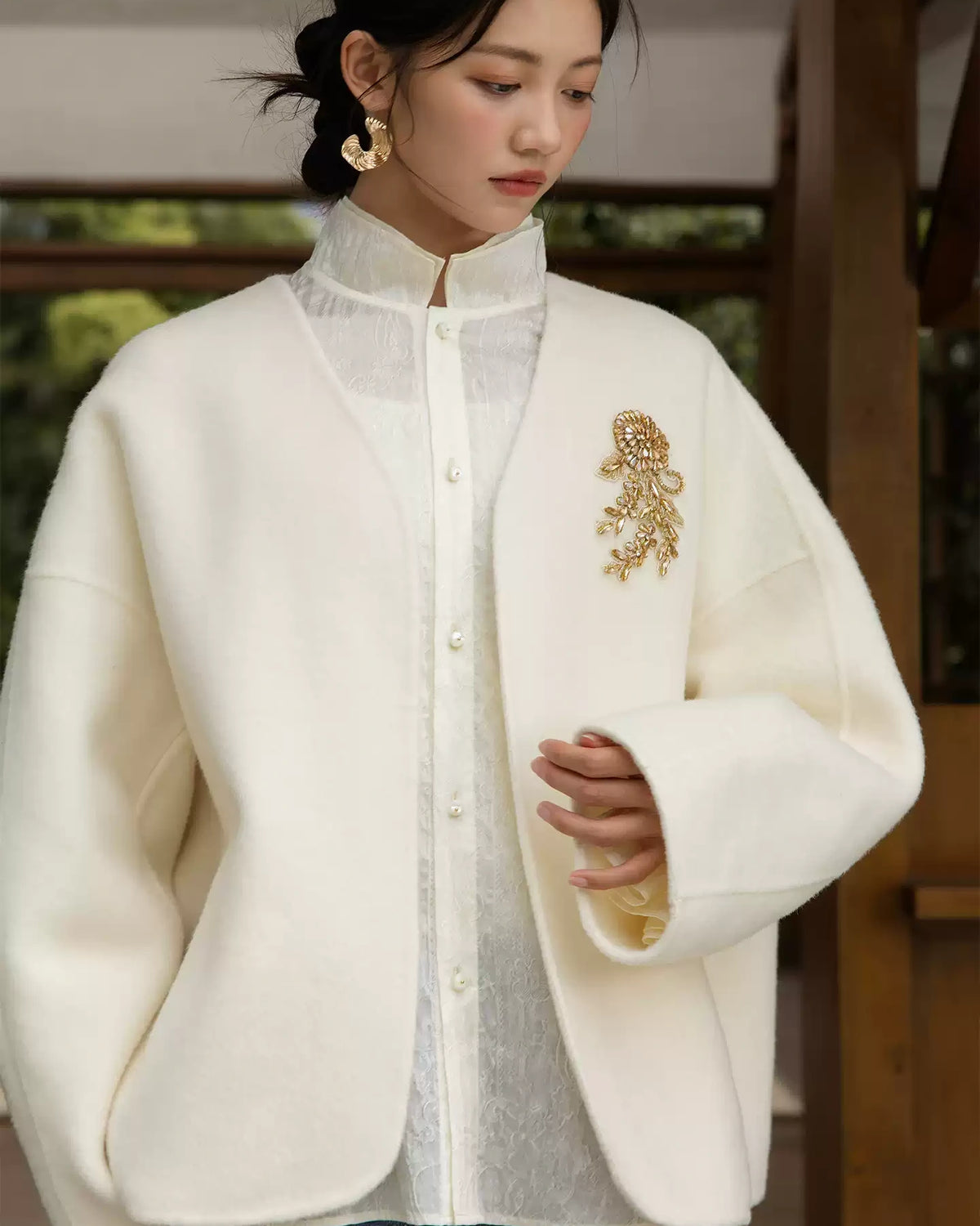 Front view of the blush pink wool coat with floral appliqué, worn over a white lace blouse and black skirt