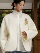 Front view of the blush pink wool coat with floral appliqué, worn over a white lace blouse and black skirt