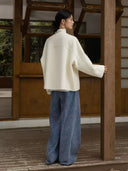 Back view of the ivory Duyao wool coat showing its curved back seam, relaxed silhouette, and long sleeves