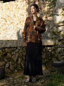 Full-length outfit featuring an earth brown and olive printed jacket over a long black dress, styled with metallic shoes.
