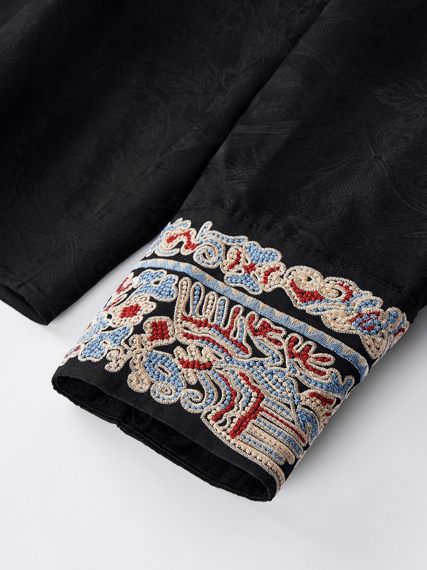 Close-up of the embroidered cuff on a black long-sleeve Cheongsam blouse, featuring multi-colored beadwork and silk-blend jacquard fabric.