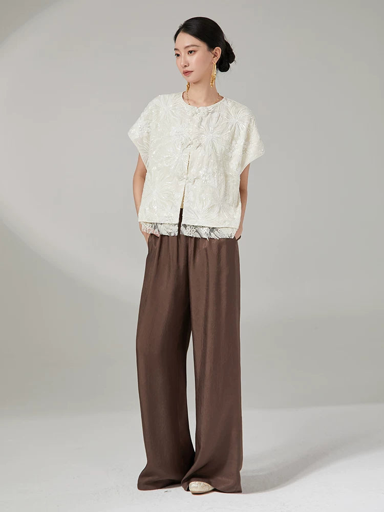 Chinese-inspired embroidered jacket paired with brown wide-leg trousers.