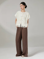 Chinese-inspired embroidered jacket paired with brown wide-leg trousers.