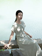 Lifestyle photo of a woman wearing a light sage embroidered maxi dress outdoors by Gambiered Silk