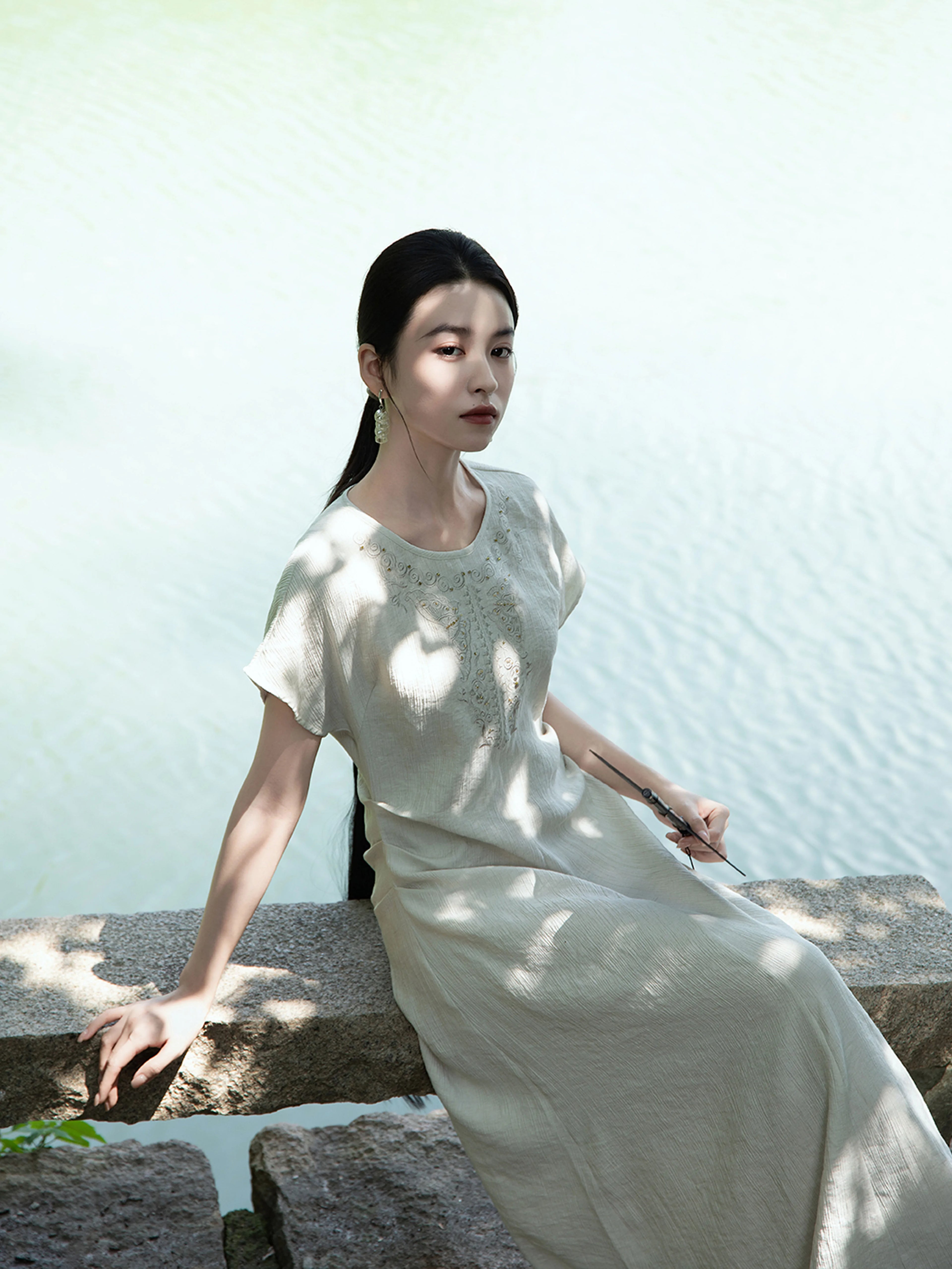 Lifestyle photo of a woman wearing a light sage embroidered maxi dress outdoors by Gambiered Silk